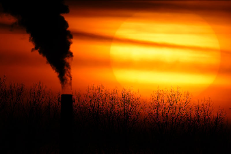 Smoke rises from a coal-fired power plant as the sun begins to set.