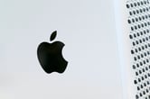 The Apple logo is displayed on a Mac Pro desktop computer