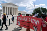 Voting rights activists march outside of the Supreme Court.