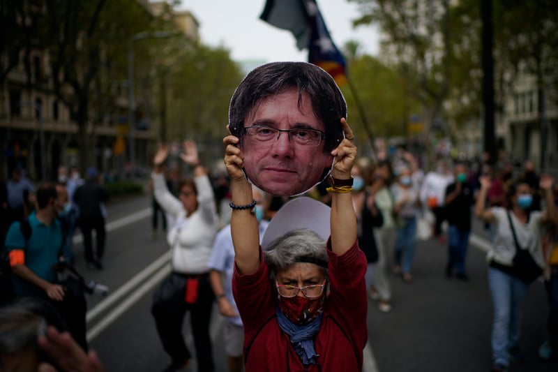 A woman holds a cardboard cut out of the head of Carles Puigdemont during a protest in support of Puigdemont.