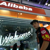 A security guard passes by the Alibaba booth at a trade show in Beijing, China.