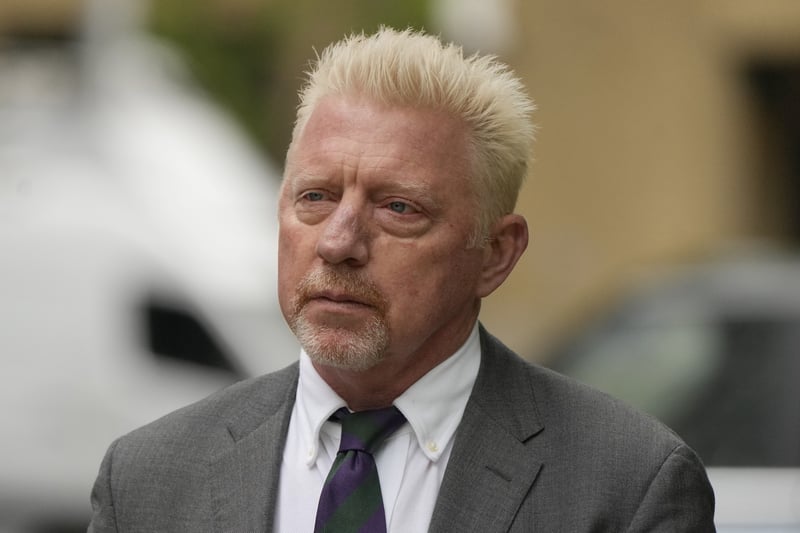 Boris Becker wears a suit while standing outside.