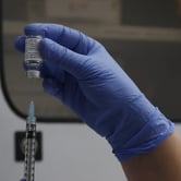 The Phase 3 Novavax Covid-19 vaccine is added to a syringe from a vial.