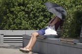 A woman uses an umbrella to shelter from the sun in London.