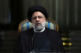 Ebrahim Raisi sits at a chair as he speaks into a microphone during a news briefing.