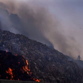 A person picks through trash as a fire rages at a landfill in India.