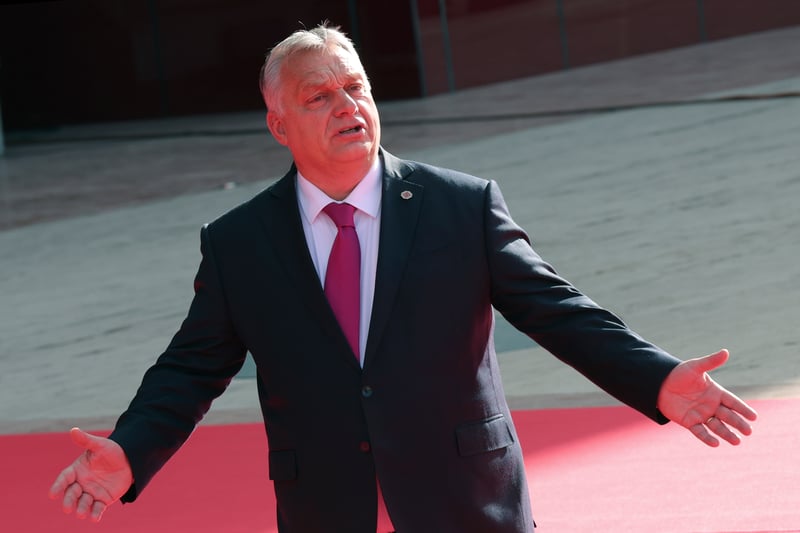 Viktor Orbán gestures while walking on a red carpet.