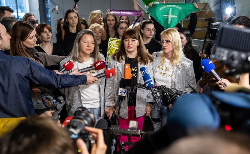 More than a dozen women stand behind Justyna Wydrzyńska as she speaks to reporters.