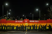 A painting showing silhouettes of more than a dozen people below the words "25 years of building peace" on the Lanark Way interface gates.