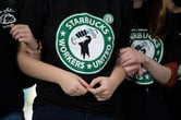 Three people wearing Starbucks Workers United shirts lock arms.
