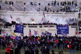 Violent insurrectionists carrying flags and wearing various Donald Trump-themed clothing items storm the U.S. Capitol.