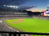 bright green baseball field lit by stadium lights at dusk