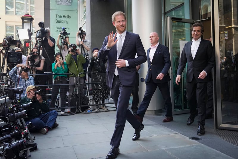 Prince Harry waves while walking by members of the media after exiting the High Court in London.