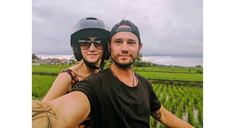 Man poses with woman wearing a helmet against the background of a green field