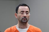 Larry Nassar wears an orange prison jump suit in a courtroom.