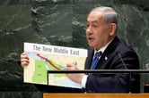 Benjamin Netanyahu draws a red line through a placard with a map of North Africa and the Middle East while giving a speech.