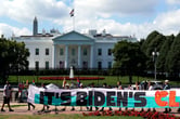 Climate activists hold a long sign while protesting outside the White House.