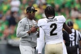 Deion Sanders and Shedeur Sanders talk during a college football game at Autzen Stadium.