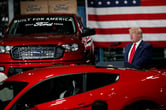 Donald Trump speaks next to a red Ford pick-up truck and a Ford sedan at one of the company's plants.