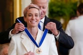 Joe Biden places the Presidential Medal of Freedom around Megan Rapinoe's neck.