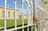 The beige Waupun Correctional Institution sits behind a wrought iron gate.