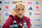 Alexia Putellas touches her head while answering questions during a news conference.