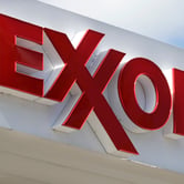 A red Exxon sign on the top of a white awning.