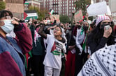 Students hold signs at a protest in support of Palestine, a young woman in the front is shouting and pointing.
