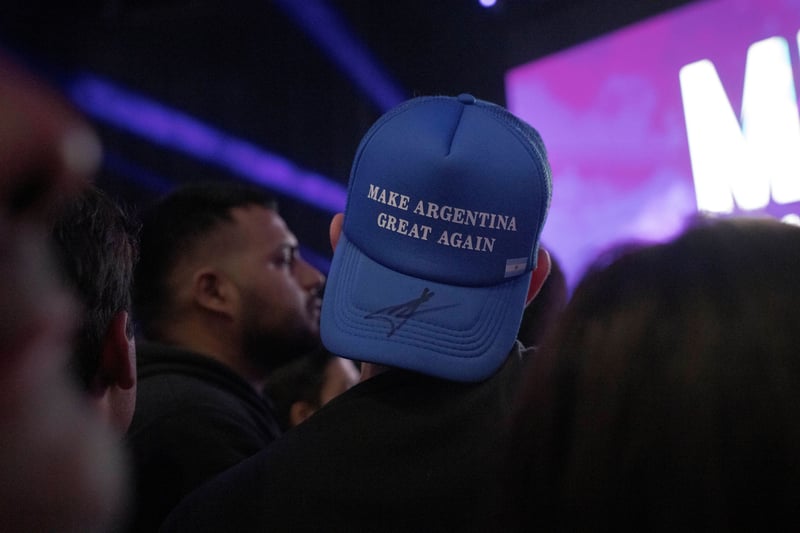 A person surrounded by a crowd wears a light blue trucker hat backwards.
