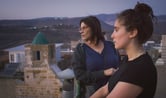 Hiam Abbass and Lina Soualem stand on top of a residential building during a scene from "Bye Bye Tiberias."