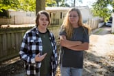 Caston Peters speaks while standing next to their mother in a yard partially covered by leaves.