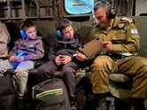 Two children and a man with headphones on a plane.