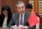 Wang Yi sits behind a desk with a small Chinese flag on it during a meeting with other foreign ministers.