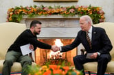 Two men shaking hands in front of a fireplace.