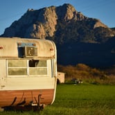 An abandoned trailer rests in a grassy field.