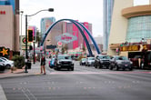 The Las Vegas Boulevard Gateway Arches, adorned with the "City of Las Vegas" sign, span across the street against a backdrop of hotels and a tour bus.