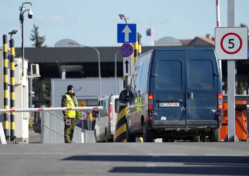 A guard stands near vehicles at a Ukraine-Poland border checkpoint.