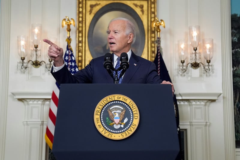 Biden stands at a presidential lectern and points.