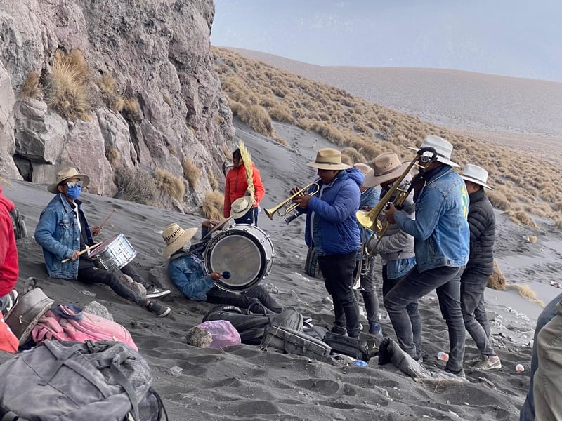 A seven piece band plays their horns and drums on a volcano. 