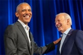 Barack Obama touches Joe Biden as both men smile.