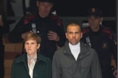 Two police officers follow Dani Alves as he walks next to a woman.