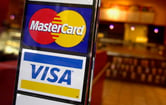 The logos for Mastercard and Visa on a sign at the entrance of a shop.