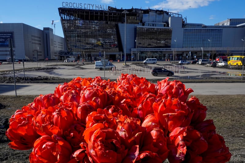 A bouquet of red flowers in front of a partially burned building.