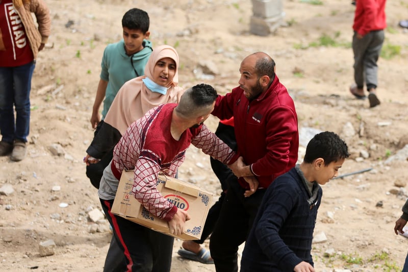 Two men struggle over a box of food aid.