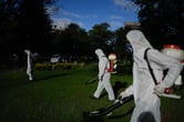 People wearing hazmats suit fumigate a field.