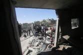 Palestinians near destroyed residential building