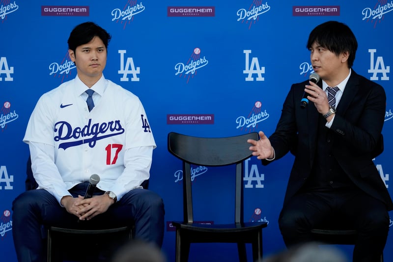 Ippei Mizuhara speaks into a microphone while sitting near Shohei Ohtani during a Los Angeles Dodgers press conference.