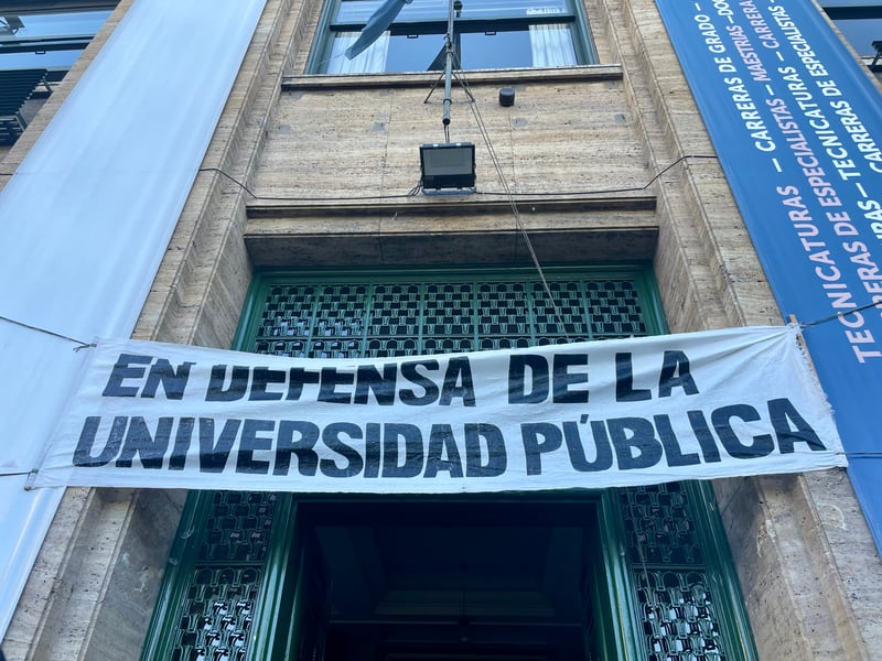 A banner on a building reads "in defense of public universities."