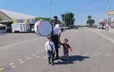 A pipe band drummer stands with two children