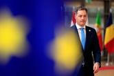 Alexander De Croo walks toward a European Union flag.